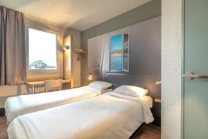 DéolsB&B HOTEL CHATEAUROUX Déols的配有窗户的酒店客房内的两张床