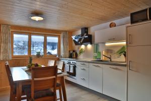 梅劳Apartments Hänsler的厨房配有白色橱柜和桌椅