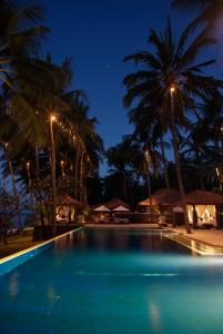 特贾库拉Spa Village Resort Tembok Bali - Small Luxury Hotels of the World的夜间棕榈树游泳池