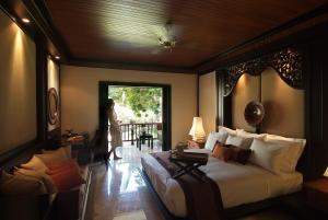 特贾库拉Spa Village Resort Tembok Bali - Small Luxury Hotels of the World的卧室配有床,女士站在窗户外