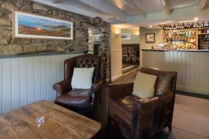 索尔瓦The Cambrian Inn的酒吧配有两张皮椅和一张桌子