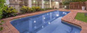 布里斯班Airport International Motel Brisbane的一座带房子的庭院中的蓝色游泳池