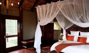 莫迪默勒Zwahili Private Game Lodge & Spa的一间卧室配有带橙色和白色枕头的天蓬床