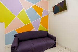 雅加达RedDoorz @ Tanjung Duren的一张沙发,墙上装饰着五颜六色