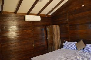 帕罗林Royal Touch Beach Huts的一间卧室设有木墙和一张带蓝色和白色枕头的床。