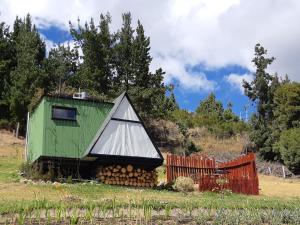 CuítivaLa Quinta Glamping - Lago de Tota的一片绿色的白色房子,有一堆木柴