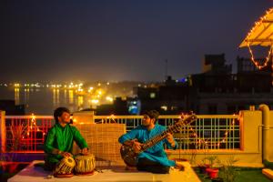 瓦拉纳西Wander Station Varanasi的两个人坐在一个摇椅上弹吉他