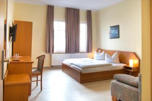 耶拿图林根霍夫酒店 的配有一张床和一把椅子的酒店客房