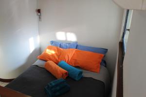 伊夫雷亚LA SERRA 211的橙色和蓝色枕头间的一张小床