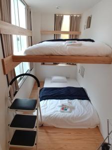 名古屋駐車場無料 Nagoya Hostel The Three Smiles Free Car Park的一间卧室配有两张双层床和椅子