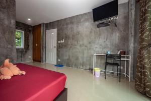 湄南海滩湄南别墅酒店的一间卧室配有红色的床,墙上配有电视