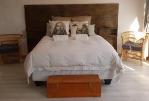 布隆方丹Emmaus Apartment的卧室配有一张白色的床,上面有肖像