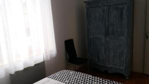 拉弗雷切Appartement Taïko的一间卧室配有一张床、一个黑色橱柜和一把椅子