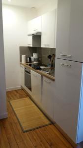 拉弗雷切Appartement Taïko的厨房铺有木地板,配有白色橱柜。