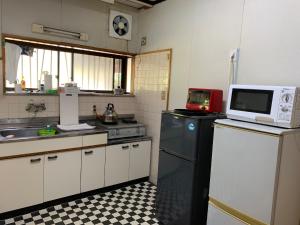 屋久岛和平民宿的厨房配有冰箱上方的微波炉