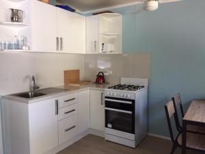 弗雷泽岛Elouera Units的厨房配有白色橱柜、炉灶和桌子。