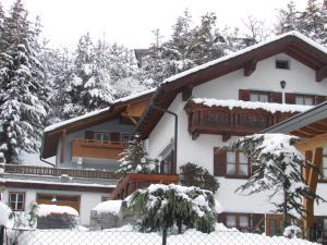 伊姆斯特Ferienhaus Tschenett的前方有栅栏的雪覆盖的房子