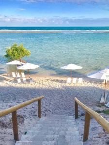 嘎林海斯港Samoa Beach Resort的海滩上设有白色的遮阳伞和椅子,还有大海