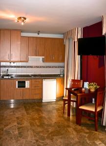 科尔多瓦弗恩特公寓酒店的厨房配有木制橱柜和一张带白色冰箱的桌子。
