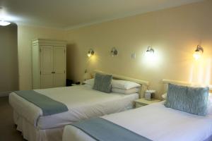 坎特伯雷坎特伯雷酒店的酒店客房,设有两张床,墙上有灯