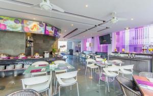 勒吉安Conjioo Hotel Kuta Formerly Instyle Hotel的餐厅设有白色的桌椅和紫色的墙壁
