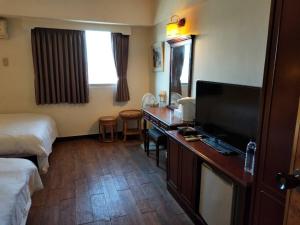 恒春古城垦丁小天地度假旅店的酒店客房配有一张书桌、一台电视和一张床