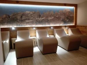 平佐洛丹尼酒店 的一间设有白色椅子和岩石墙的等候室