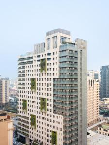 台中市顺天环汇酒店的一座高大的白色建筑,上面有绿色植物