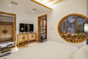 张家界Su Xin Resort Inn的一间卧室配有一张床、一台电视和一面镜子