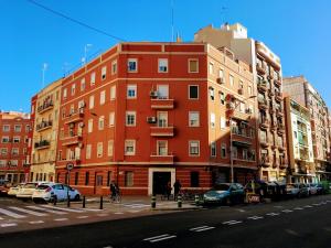 瓦伦西亚瓦伦西亚麦尔顶层公寓的一条城市街道上的红色建筑,有停车的汽车