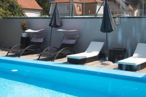 莱布尼茨洛美霍夫酒店及餐厅的一组椅子和遮阳伞,位于游泳池旁