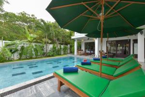 会安安邦海滩别墅的一个带绿伞和躺椅的游泳池