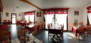 Aillon-le-JeuneHôtel du Soleil的用餐室配有桌椅和红色窗帘