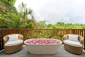塔巴南霎哈嘉萨瓦度假别墅的两把椅子和一个庭院内带喷水的浴缸