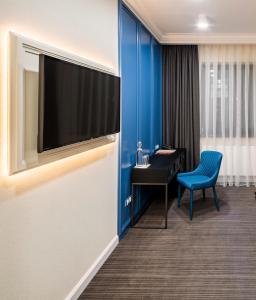 利沃夫Hotel Rafael Готель Рафаель的一间配有电视和蓝色墙壁的客房