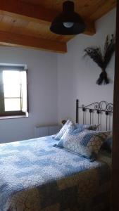 里瓦德奥A Minguxaina的一间卧室配有一张带蓝色毯子的床和窗户。