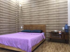 大叻Ruby Dalat Hostel的一间卧室配有一张带紫色毯子的床