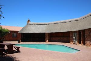 金伯利Kalahari Lodge Kimberley的一座带游泳池和野餐桌的建筑