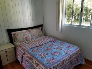 乌鲁佩马Casa de Campo Passo do Tatu的一间卧室配有一张带被子的床和一扇窗户
