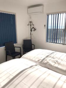 直岛町UOGASHI 7070 Ocean View的卧室配有白色的床和2把椅子