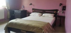 Bab EzzouarRoza Hotel的一间卧室配有一张带木制床头板和一张桌子的床。