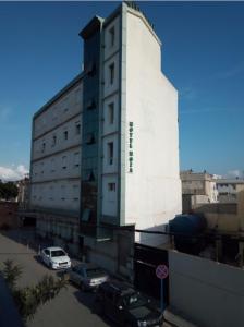 Bab EzzouarRoza Hotel的一座高大的白色建筑,汽车停在停车场