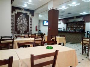 Bab EzzouarRoza Hotel的一间带桌椅的餐厅和一间酒吧