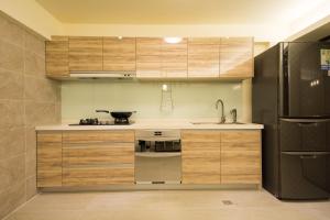 礁溪怡然小筑的厨房配有木制橱柜和不锈钢冰箱。
