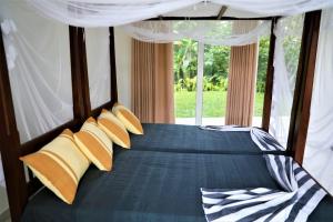 希克杜沃Villa Kaya Guest House的一间卧室配有一张带黄色枕头的床和一扇窗户