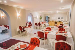 卡罗利嫩西尔Hotel Carolinensiel Doan的一间设有白色桌子和红色椅子的餐厅
