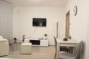布拉格H+ Apartman Letiště Praha的客厅配有桌子,墙上配有电视
