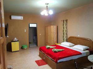 素可泰Baandin resort的一间卧室配有一张带红色床单和一张桌子的床。
