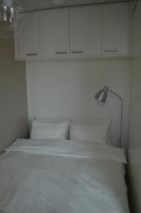 罗瓦涅米Aurora Haven Rovaniemi Modern DT Apartment -Self Check-In & Free Wifi-的一张带灯具和白色橱柜的白色床