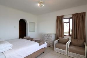 普利登堡湾Villa Granada的卧室配有床、椅子和窗户。
